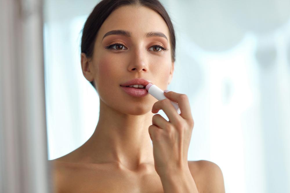 Model applying lipstick in the mirror