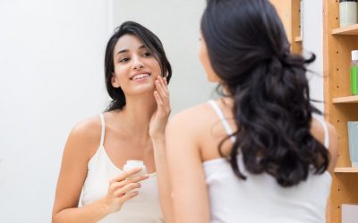 Model putting on face cream in the mirror