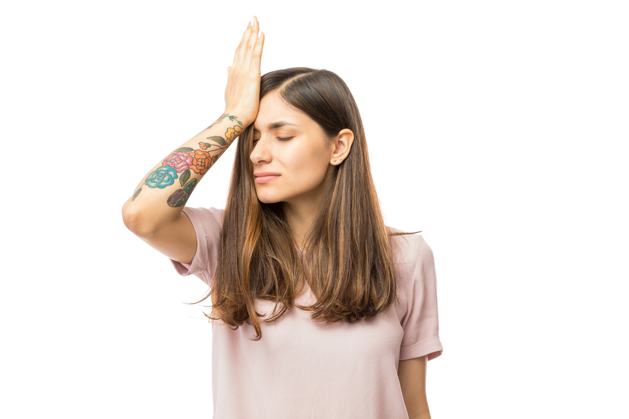 Woman realizing mistake and keeping hand on head over white background