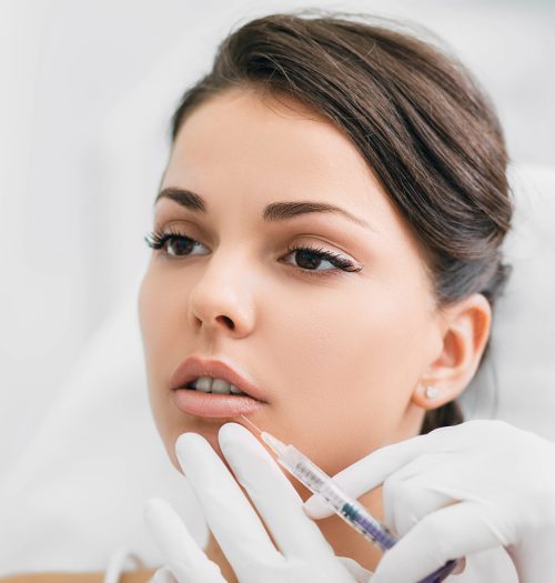 woman having lip injections, a prick of a syringe for the beauty lips. lip augmentation