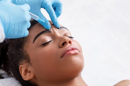 Young woman receiving Botox injection between her eyebrows.