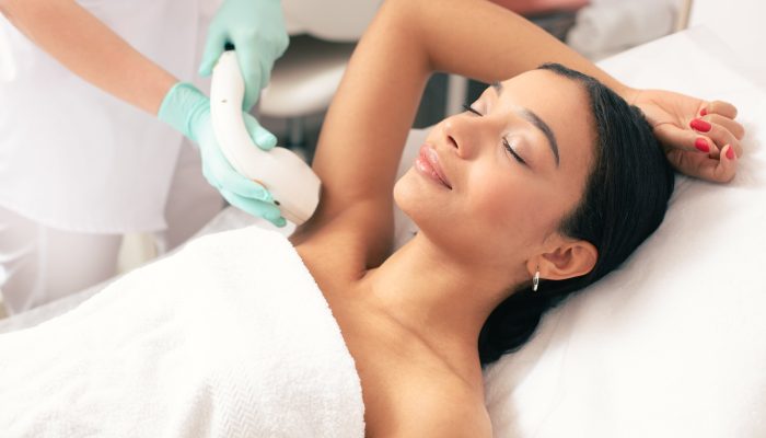 Woman receiving laser hair removal at a clinic. Smiling, happy.