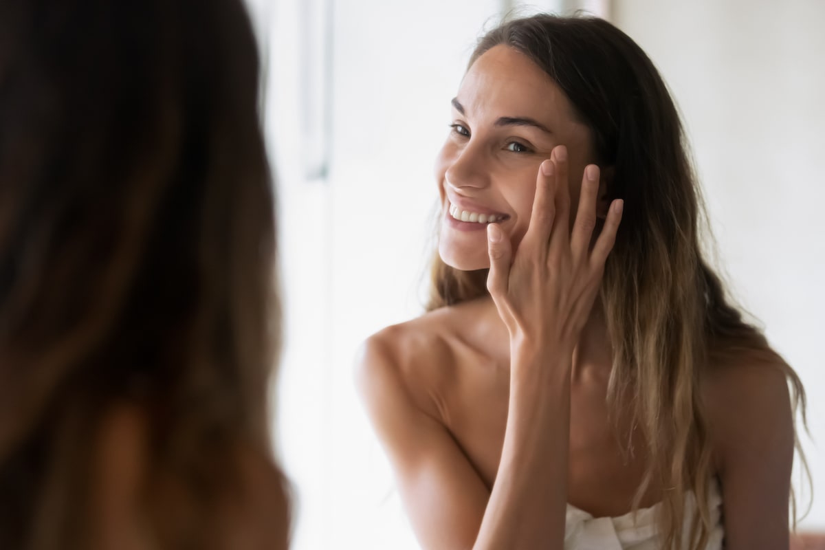 woman looking in the mirror, admiring her great skin after the Morpheus8 treatment