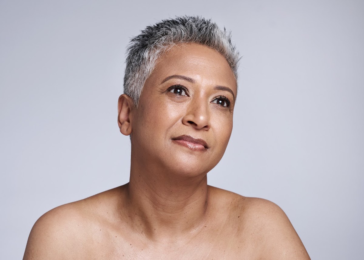 Senior woman with short gray hair enjoying skincare and wellness, showcasing natural beauty with a serene expression.