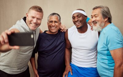 Group of four diverse men smiling and taking a selfie in athletic wear.