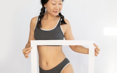 Woman in gray athletic wear holding a white frame against a neutral background.