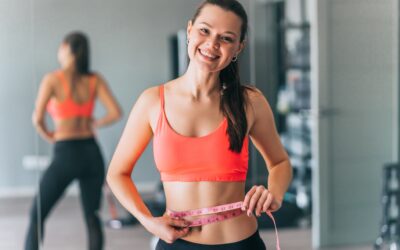 Woman measuring waist with tape in gym
