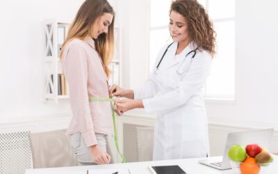 Nutritionist measuring woman’s waist with tape