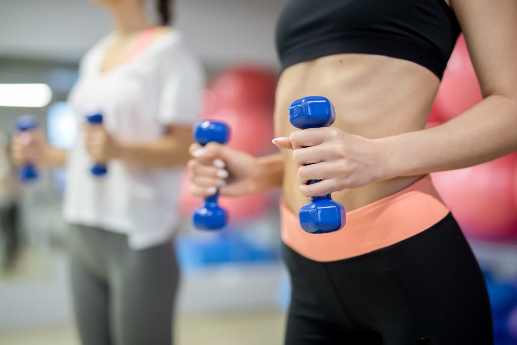 Women exercising with blue dumbbells in gym