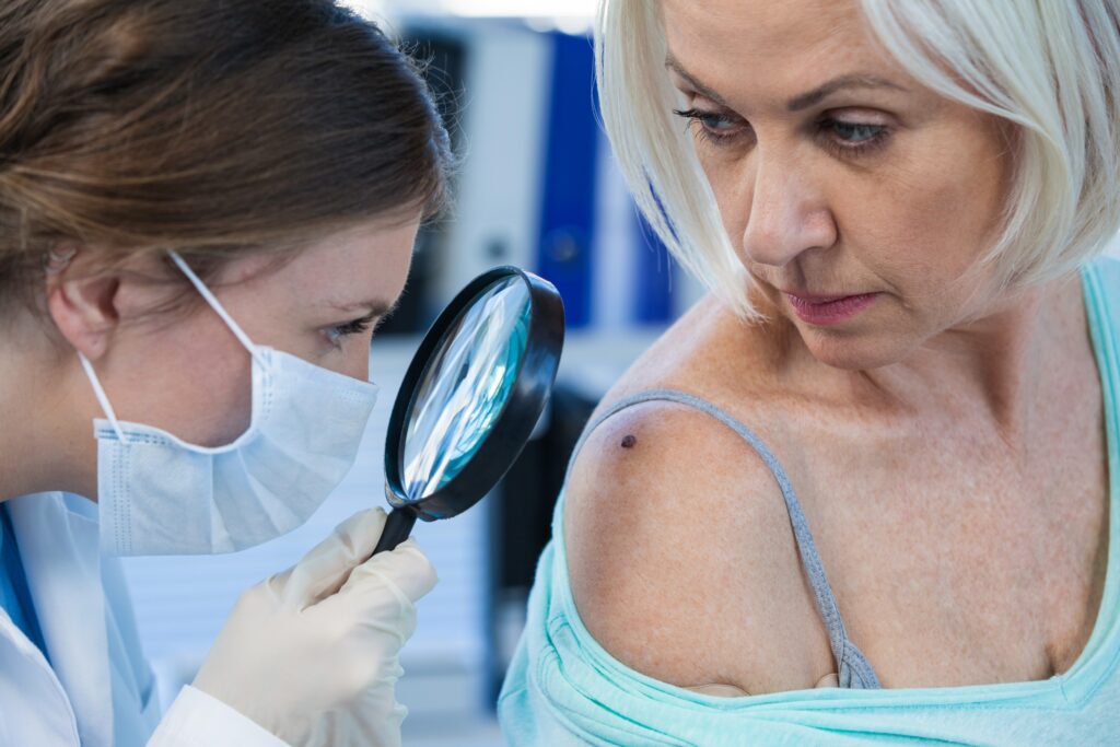 Dermatologist checking mole on woman’s shoulder