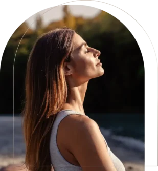 Woman practicing mindfulness meditation outdoors with eyes closed Woman meditating peacefully near water outdoors