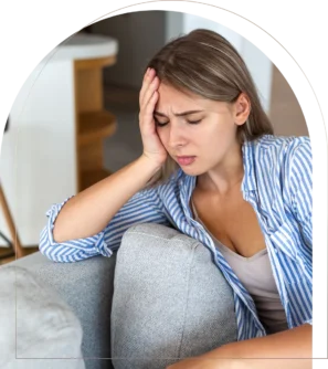 Woman with headache holding head on couch
