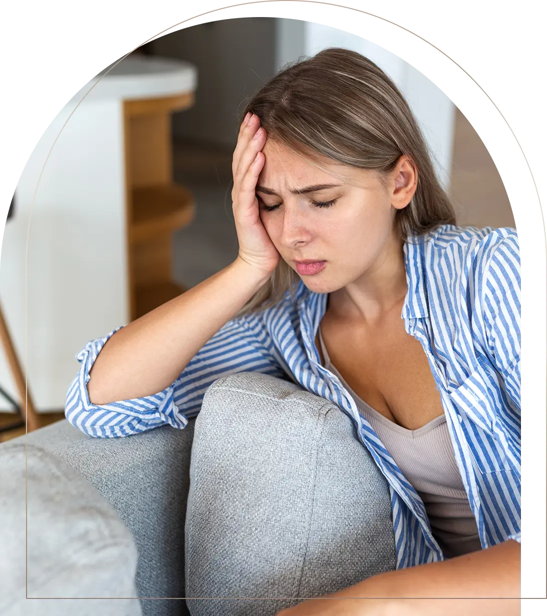 Woman with headache holding head on couch