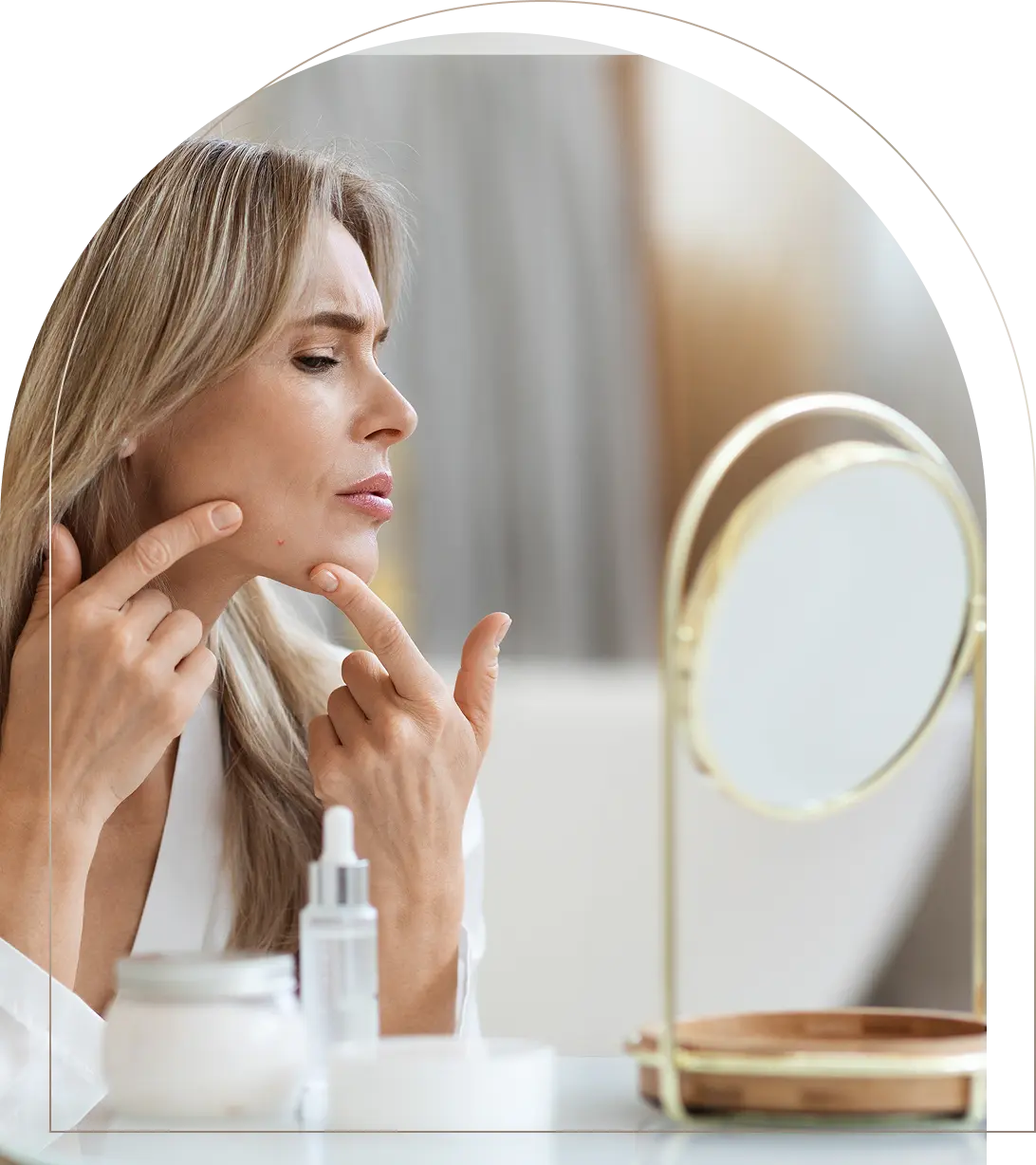 Middle-aged woman examining acne on chin in front of mirror Woman checking acne on chin in mirror
