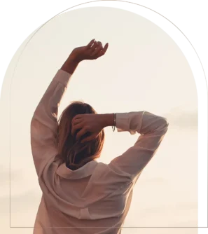 Woman stretching arms upward at sunset