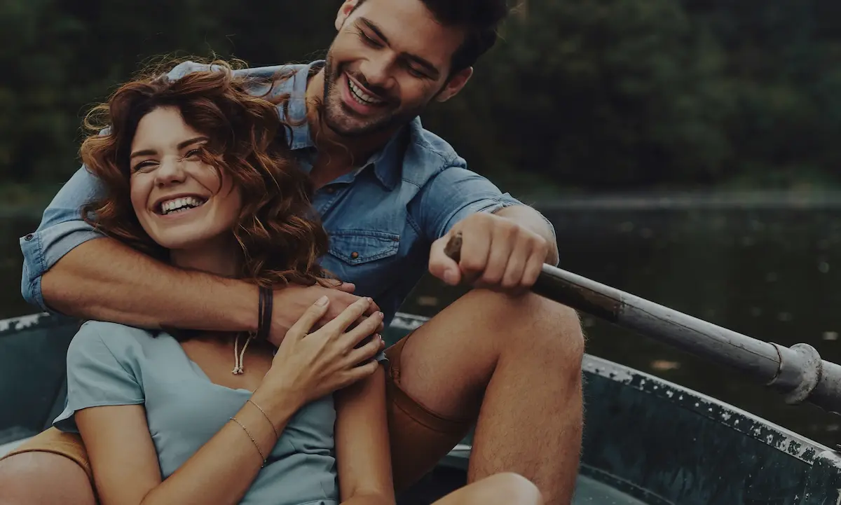 Couple smiling rowing boat on lake outdoors